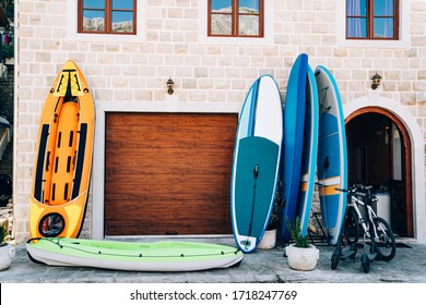 Sports travel equipment rental store - rubber boats, inflatable canoes and kayaks, gliding boards, bicycles and electric scooters. A building with a garage and brown windows, made of white stone