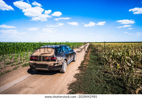 Sports utility vehicle on a dusty road in\
countryside in summer.