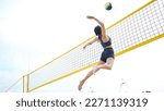 Sports, volleyball and woman jump at beach to hit ball in competition, game or match. Training, exercise and female athlete jumping for spike in tournament for workout, fitness and health at seashore