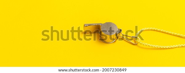 Sports whistle on yellow background. Concept -\
sport competition, referee, statistics, challenge. Basketball,\
handball, futsal, volleyball, soccer, baseball, football and hockey\
referee whistle