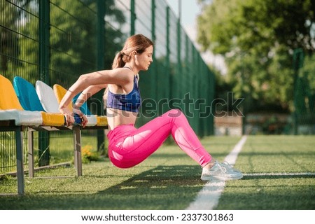 Sports woman is doing warming exercises on the stadiun on the green lawn