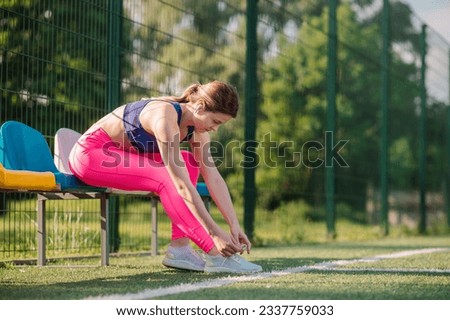 Sports woman is doing warming exercises on the stadiun on the green lawn