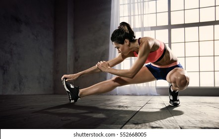 Sports. Woman at the gym doing stretching exercises and smiling on the floor