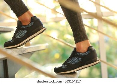 Sports woman legs in sneakers on stairs