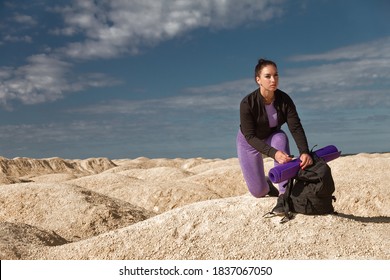 Sports Woman Single Hiker Sits On One Knee With Backpack On Mountain And Looks Into Distance, Concept Turism, Wellness Turist