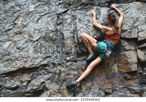 Sports Woman With slim fit body Climbing The\
Rock Having Workout In Mountains. rock climbing hard moves,\
searching holds,\
overhand