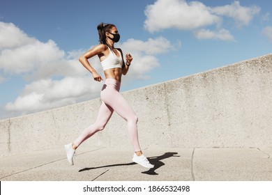 Sports Woman Wearing Face Mask Running Outdoors In The Morning. Female Athlete In Running Attire Exercising In Morning With A Face Mask On.