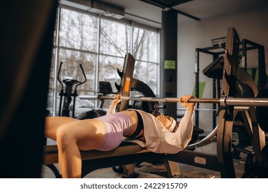 Sports young woman doing exercises with barbell on bench in the gym. Bar Bench Press. High quality photo - Powered by Shutterstock