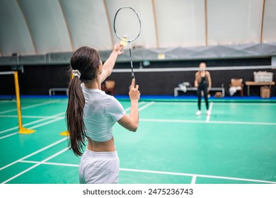 Sports young women with racket and shuttlecock is exercising, playing in badminton on inside court. High quality photo - Powered by Shutterstock