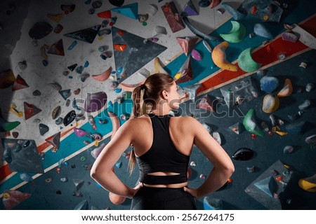 Sportsman athlete climber young woman standing back against steep wall in climbing gym indoors. Extreme sports and bouldering concept