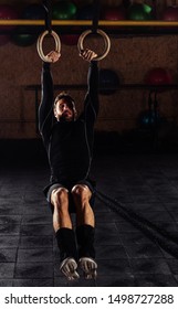 The sportsman carries out difficult exercise, sports gymnastics. Ring dip Cross fit exercise, low key, dark image, high contrast