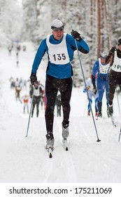 Sportsman in classic style cross country skiing race, competitors following