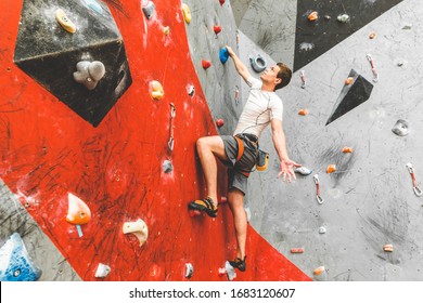 Sportsman climber moving up on steep rock, climbing on artificial wall indoors. Extreme sports and bouldering concept - Powered by Shutterstock