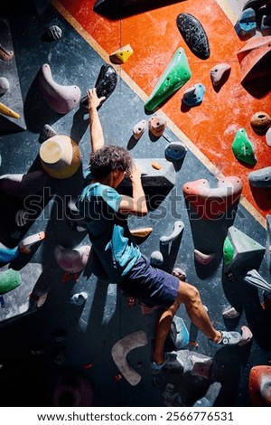 Sportsman climber moving up on steep wall in climbing gym indoors. Extreme sports and bouldering concept