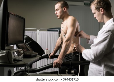 Sportsman during medical test standing on treadmill and doctor in white uniform