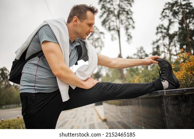 Sportsman During Outdoor Workout, Man Wearing Sports Outfit Warming Up Muscles, Doing Side Squat On One Leg, Enjoying Active Lifestyle Outside In Park