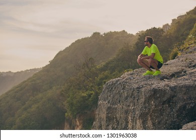 Sportsman making pause after workout on a tropical cliff. - Powered by Shutterstock