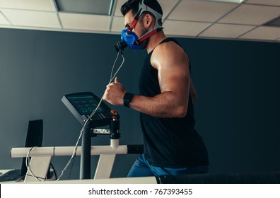 Sportsman with mask running on treadmill. Male athlete in sports science lab measuring his performance and oxygen consumption.