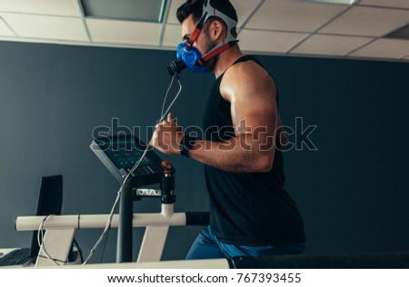 Sportsman with mask running on treadmill. Male athlete in sports science lab measuring his performance and oxygen consumption.