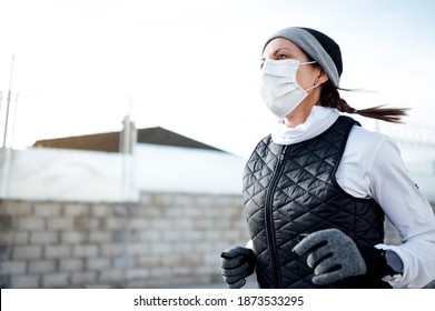 Sportsman with mask running through the industrial zone in winter as the sun rises.