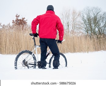 Sportsman With Mountain Bike Lost In Snow. Lost Path  In Deep Snowdrift.  Snow Flakes Melting On Dark Off Road Tyre.  Winter Weather In The Field.