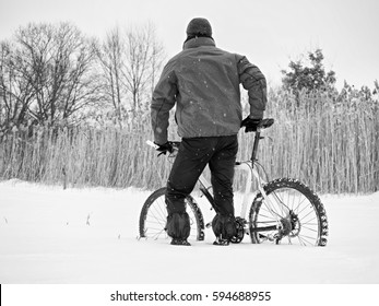 Sportsman With Mountain Bike Lost In Snow. Lost Path  In Deep Snowdrift.  Snow Flakes Melting On Dark Off Road Tyre.  Winter Weather In The Field.