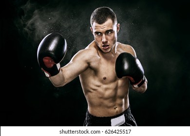 Sportsman muay thai boxer fighting in gloves in boxing cage. Isolated on black background with smoke. Copy Space.