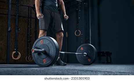 Sportsman performing weight lifting exercise at gym, croped shot, low angle view focus on barbell.