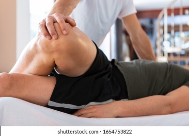 A sportsman receiving medical massage of legs. A young man lying on the massage table and having a treating leg massage in the medical center - Powered by Shutterstock