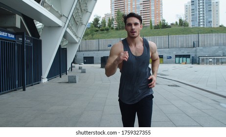 Sportsman Running At Cardio Training Outdoor In Slow Motion. Front View Of Athlete Man Jogging On Urban Street. Close Up Male Runner Training Run Outdoor. Sport Man Running At City Street