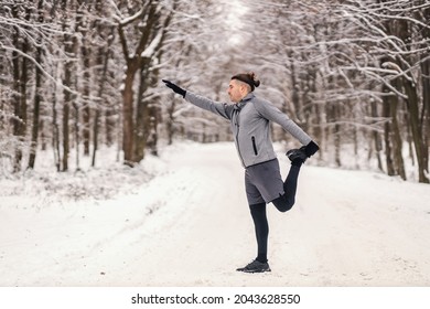 Sportsman In Shape Doing Stretching And Warmup Exercises At Snowy Winter Day. Balance, Healthy Life, Winter Fitness