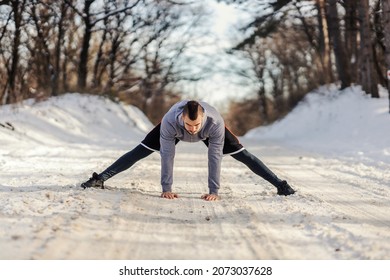 Sportsman In Shape Standing On Snowy Path In Nature And Doing Warmup And Stretching Exercises. Winter Fitness, Flexibility, Healthy Life