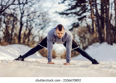 Sportsman In Shape Standing On Snowy Path In Nature And Doing Warmup And Stretching Exercises. Winter Fitness, Flexibility, Healthy Life