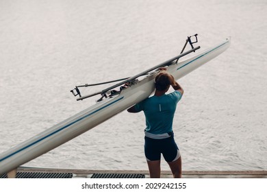 Sportsman Single Scull Man Rower Carrying Boat To Competition On Lake Water