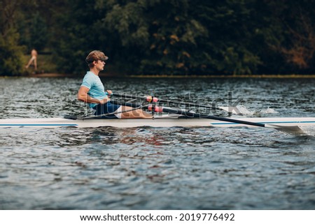 Sportsman single scull man rower rowing technique on boat. Paddle oar splash movement