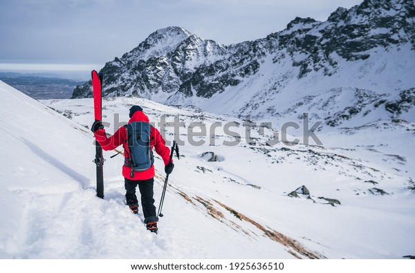 Sportsman standing with ski\
sticks on snow in mountains. Fantasy Adventure Composite of Man\
Hiking on top of a rocky mountain peak. Courage, determination,\
extreme sport