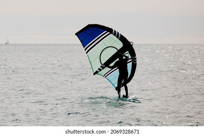 sportsman with wingfoil sailing, in the sea