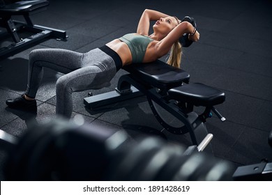 Sportsperson breathing heavily while putting her back on a weights bench and getting a disk behind a head - Powered by Shutterstock