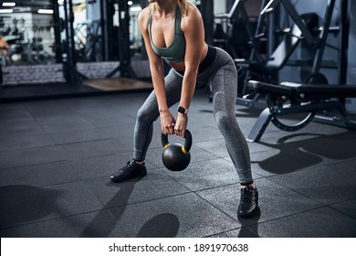 Sportsperson performing a kettlebell sumo squat with her feet fixed firmly on a wider than shoulder-width level - Powered by Shutterstock