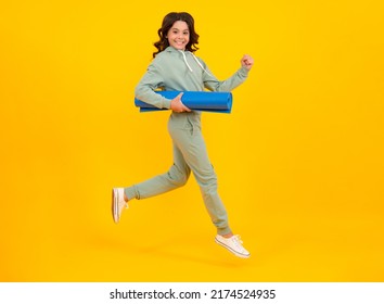 Sportswear Advertising Concept. Run And Jump. Teenager Child Girl In Tracksuits Jogging Suit Posing In The Studio Hold Fitness Mat.