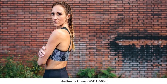 Sportswoman With Boxer Braids Posing In Front Of A Brick Wall