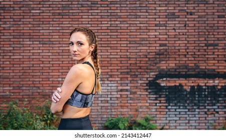 Sportswoman With Boxer Braids Posing In Front Of A Brick Wall