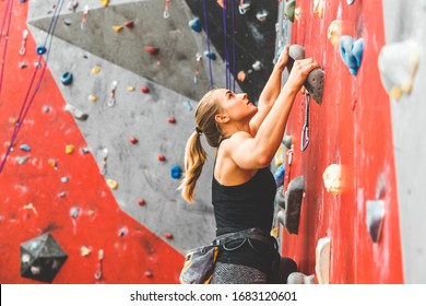 Sportswoman climber moving up on steep rock, climbing on artificial wall indoors. Extreme sports and bouldering concept - Powered by Shutterstock