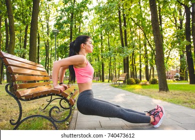 The sportswoman do exercise with a bench in the park