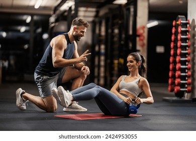 A sportswoman is dong russian twist with her personal trainer in a gym. - Powered by Shutterstock