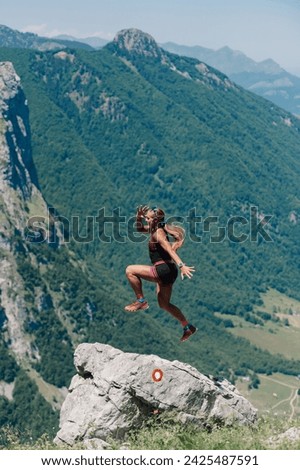 A sportswoman is jumping and skyrunning in rocky mountains in wild nature. A fit skyrunner is practicing skyrunning that includes trail running and mountaineering in wild mountains. Copy space.