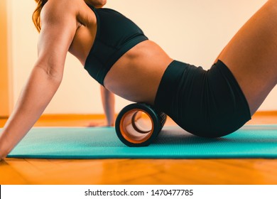 Sportswoman Massaging Lower Back With Foam Roller