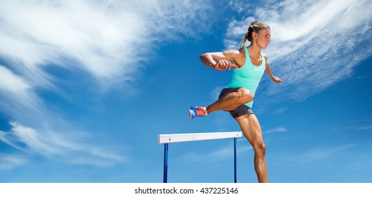Sportswoman practising the hurdles against view of a blue sky - Shutterstock ID 437225146