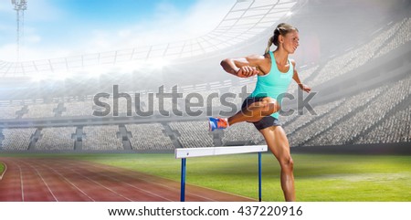 Sportswoman practising the hurdles against view of a stadium