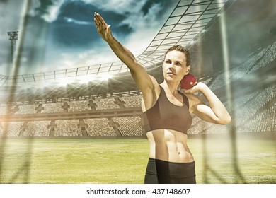 Sportswoman practising the shot put against view of a stadium - Powered by Shutterstock